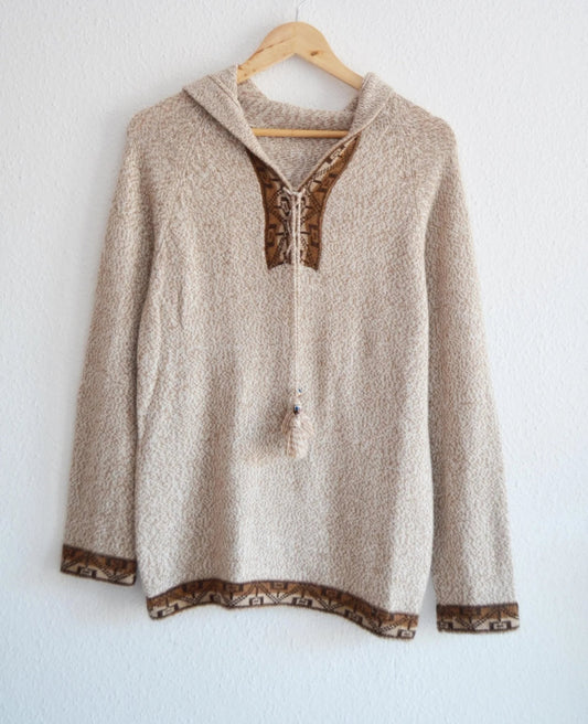 Handmade beige alpaca sweater with brown patterned trim and hood on wooden hanger.