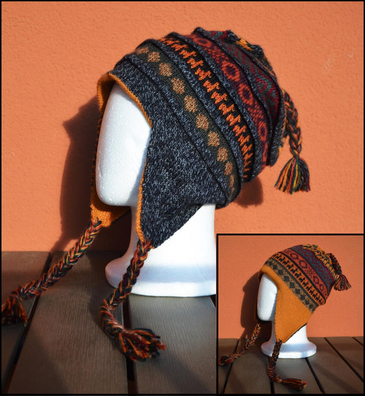 Handmade alpaca chullo hat with earflaps in black, orange, and red geometric patterns.