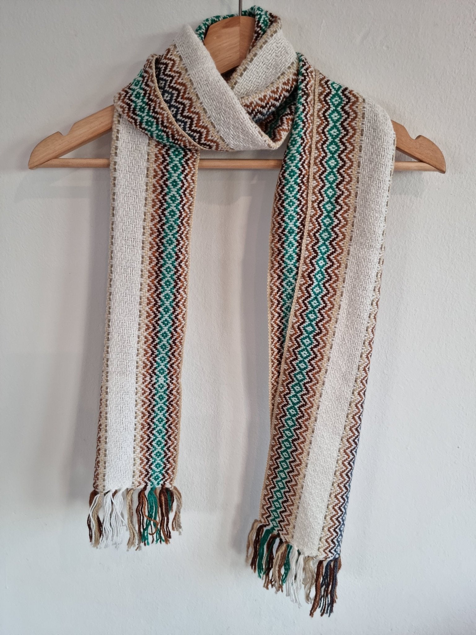 Handmade alpaca wool shawl in white with brown, teal, and orange geometric patterns and fringed ends.