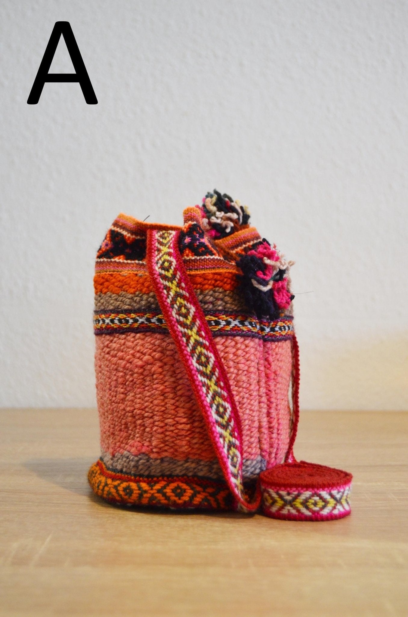 Handmade small alpaca shoulder bag with vibrant red and orange traditional Andean patterns.