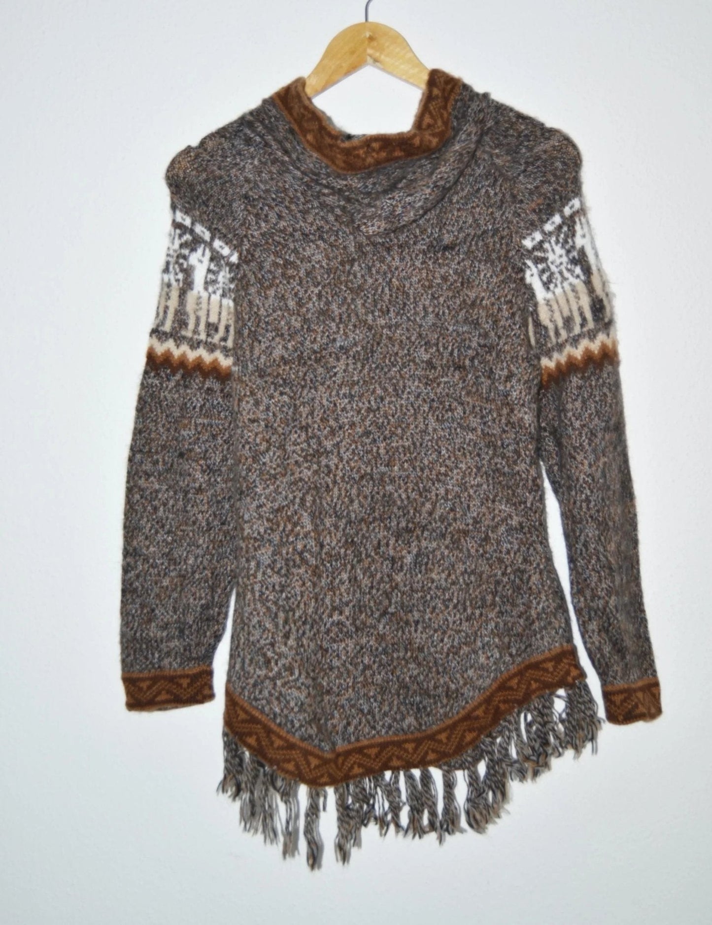 Handmade alpaca wool sweater with brown accents and fringe hem, featuring traditional patterns on sleeves.