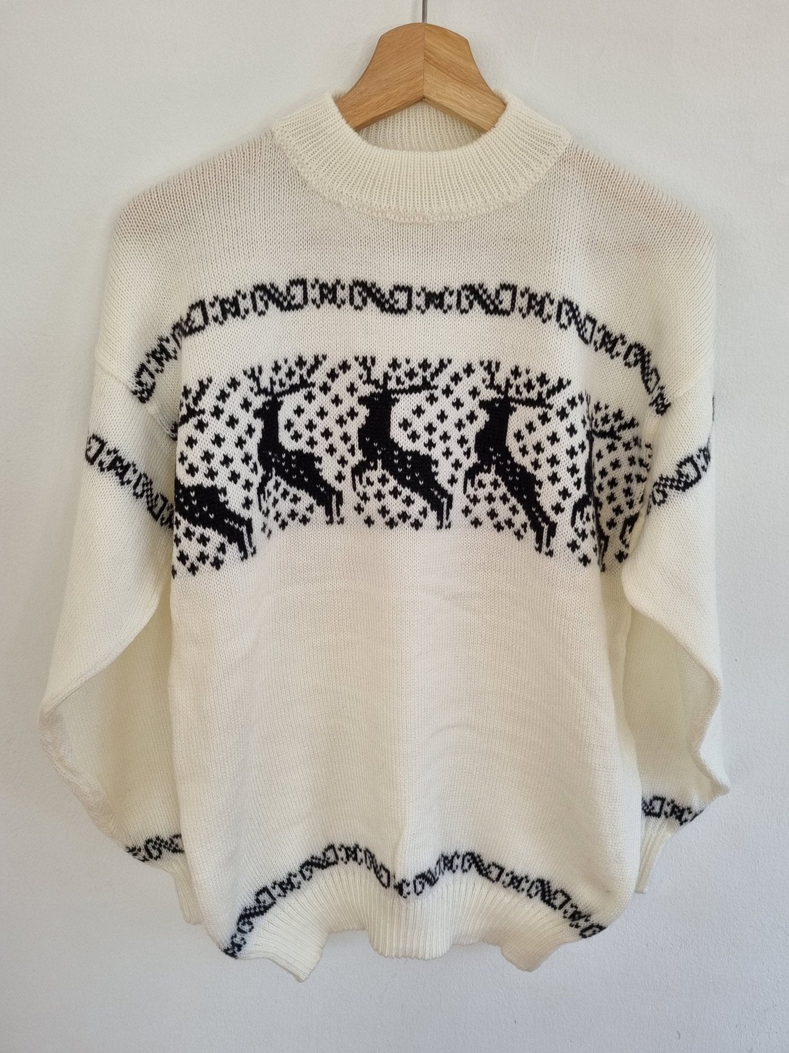 Handmade white alpaca sweater with black llama pattern and high neckline.