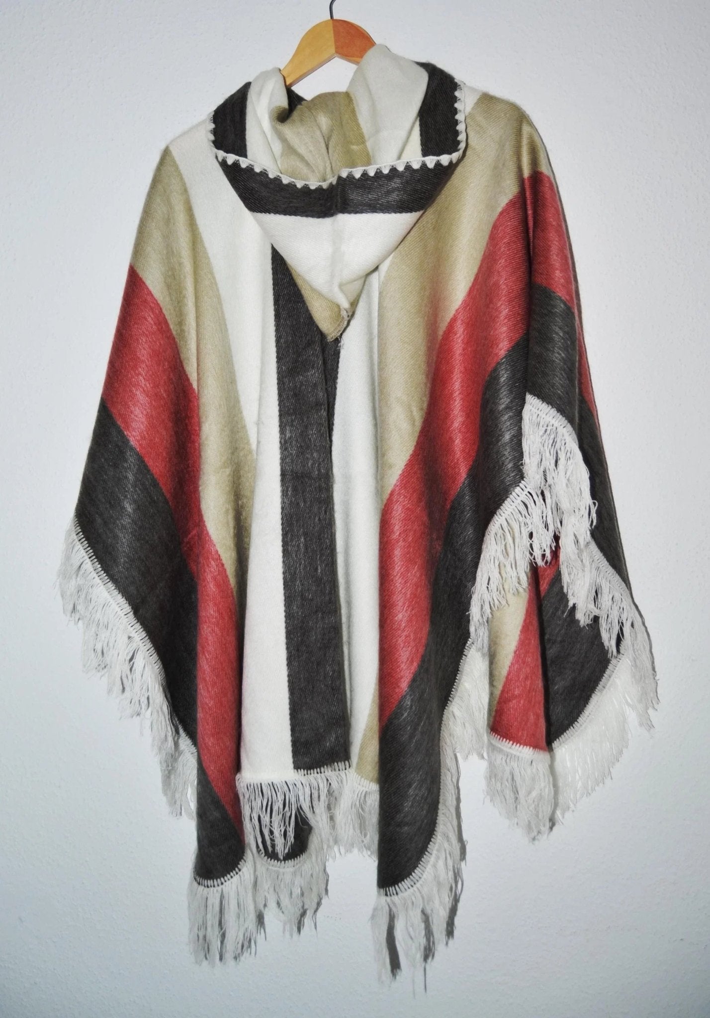 Handmade alpaca wool hooded poncho with red, black, and beige stripes and fringe trim.