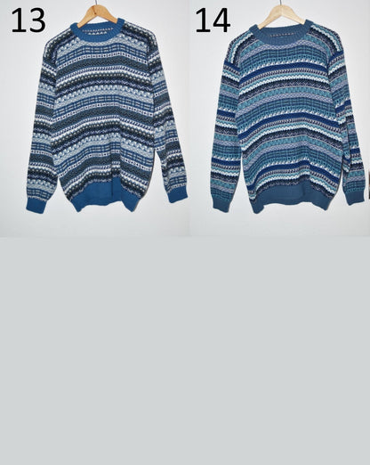 Two handmade alpaca wool sweaters in blue and white patterns hanging side by side with long sleeves and ribbed cuffs.