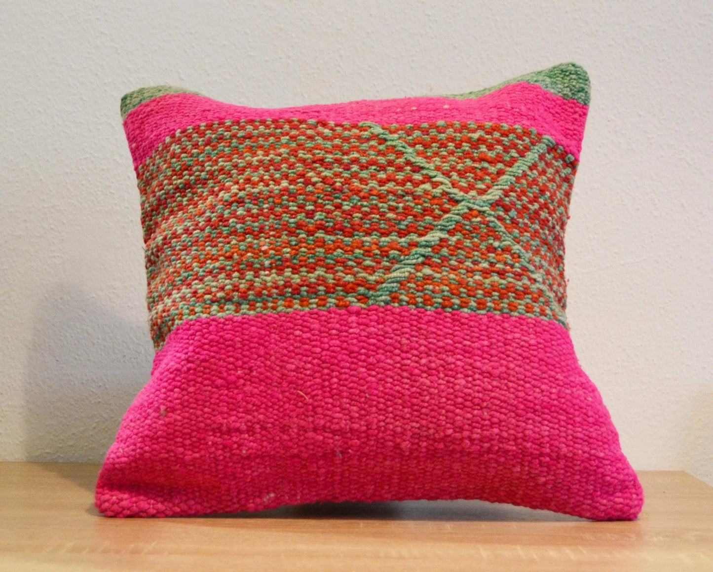 Handmade Peruvian pillow with woven alpaca fabric in bright pink and earthy tones with geometric patterns.