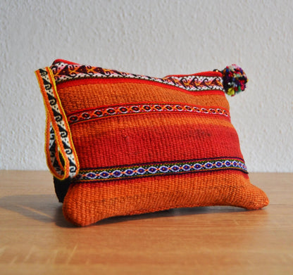 Handmade orange alpaca pouch with colorful woven ethnic patterns and zipper closure.