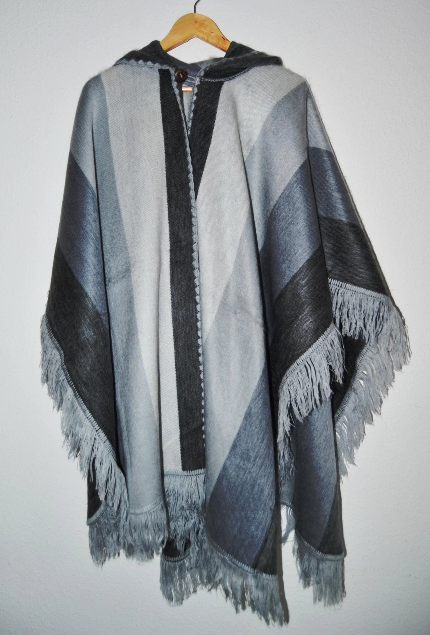 Handmade alpaca wool hooded poncho with gray and black gradient stripes and fringe trim.