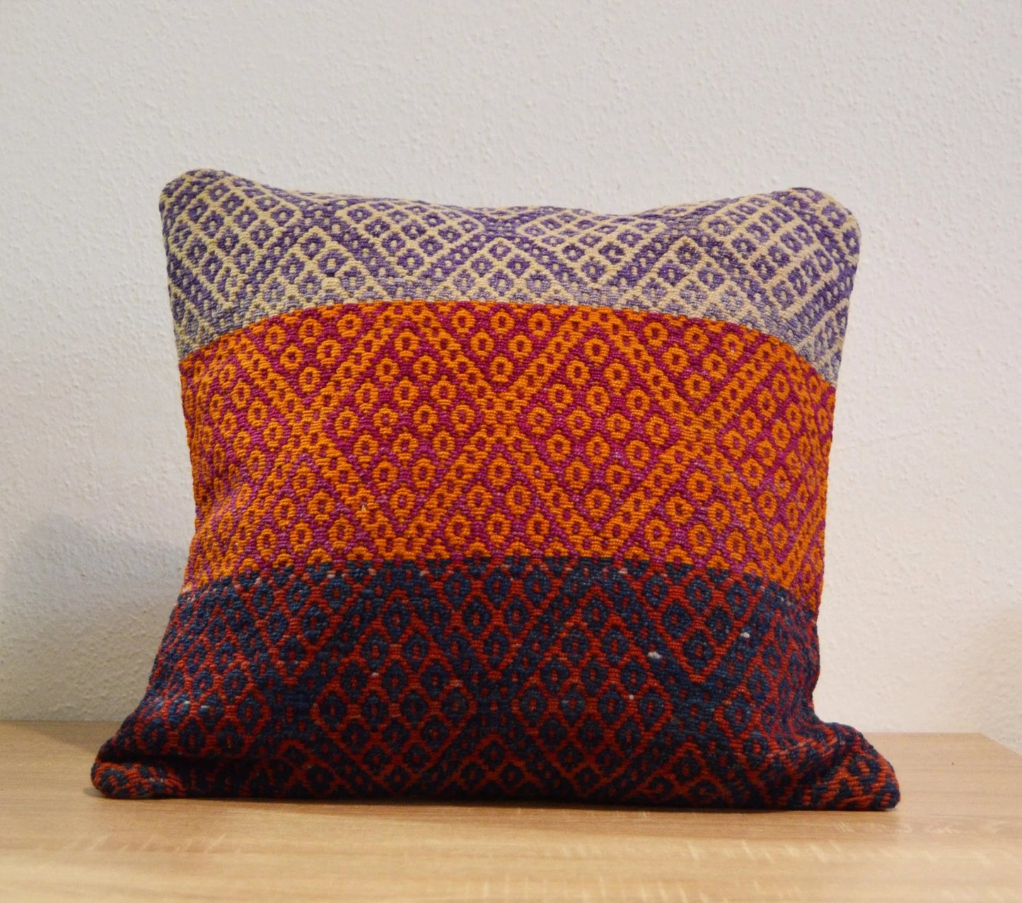 Handmade Peruvian pillow with colorful geometric alpaca weave in red, blue, and purple tones.