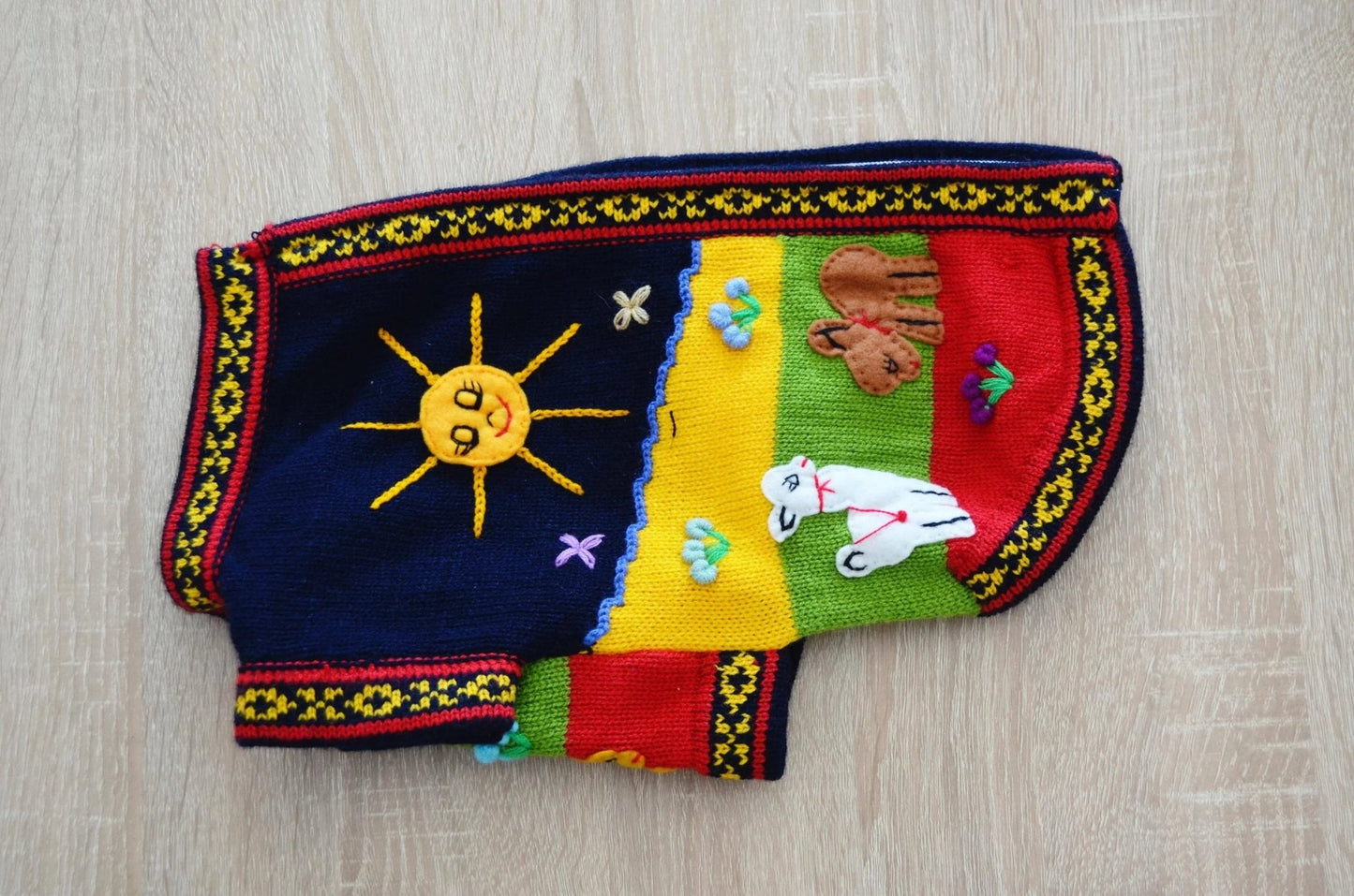 Handmade alpaca dog sweater in navy blue, yellow, green, red with sun and floral embroidery.
