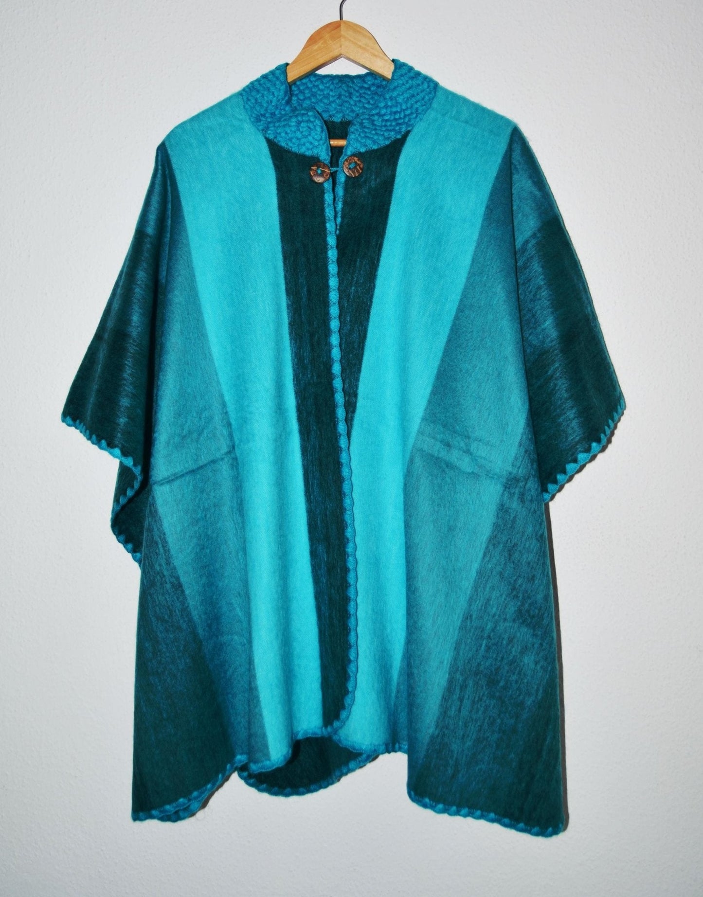 Handmade alpaca wool poncho shawl in turquoise and teal with front buttons and textured patterns.
