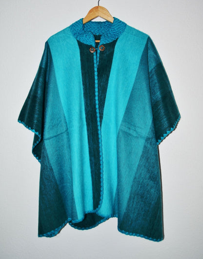 Handmade alpaca wool poncho shawl in turquoise and teal with front buttons and textured patterns.