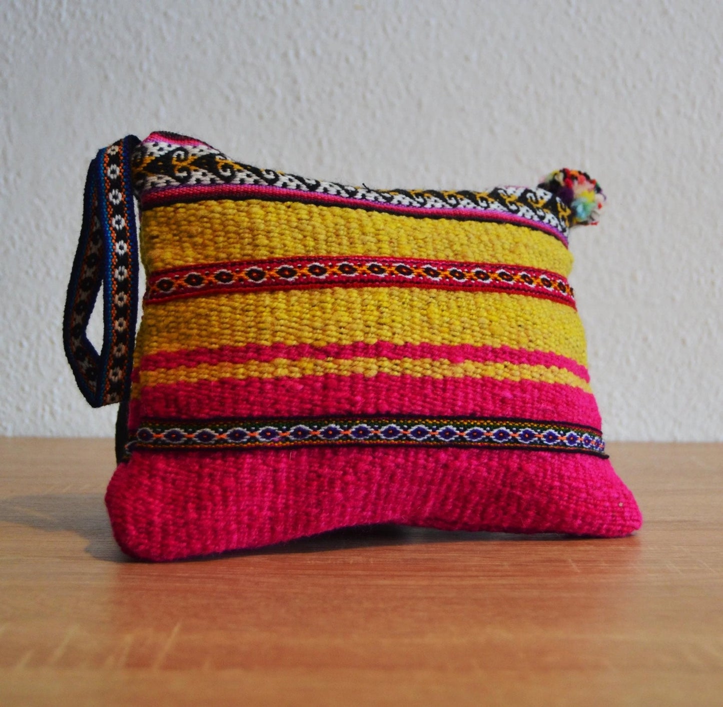 Handmade alpaca small zippered pouch in vibrant yellow, pink, and orange with ethnic woven patterns and pom-pom zipper pull.