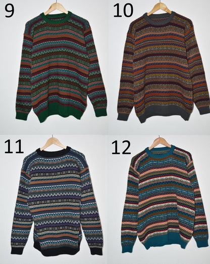Four handmade alpaca sweaters in striped patterns with earth tones, blue, and green, displayed on hangers.
