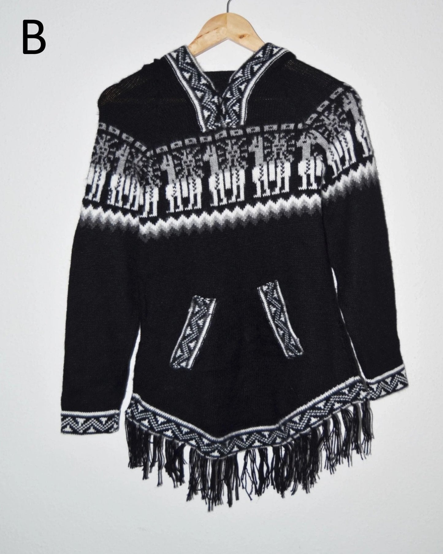 Black and white handmade alpaca sweater with llama patterns, front pockets, fringed hem, and hood.