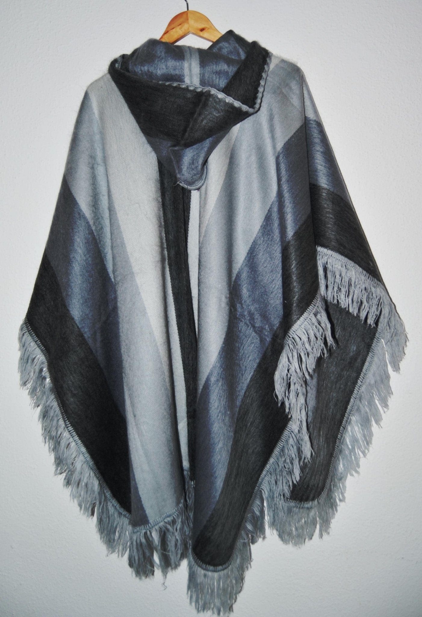 Handmade alpaca wool hooded poncho with gray and black geometric patterns and fringe trim.