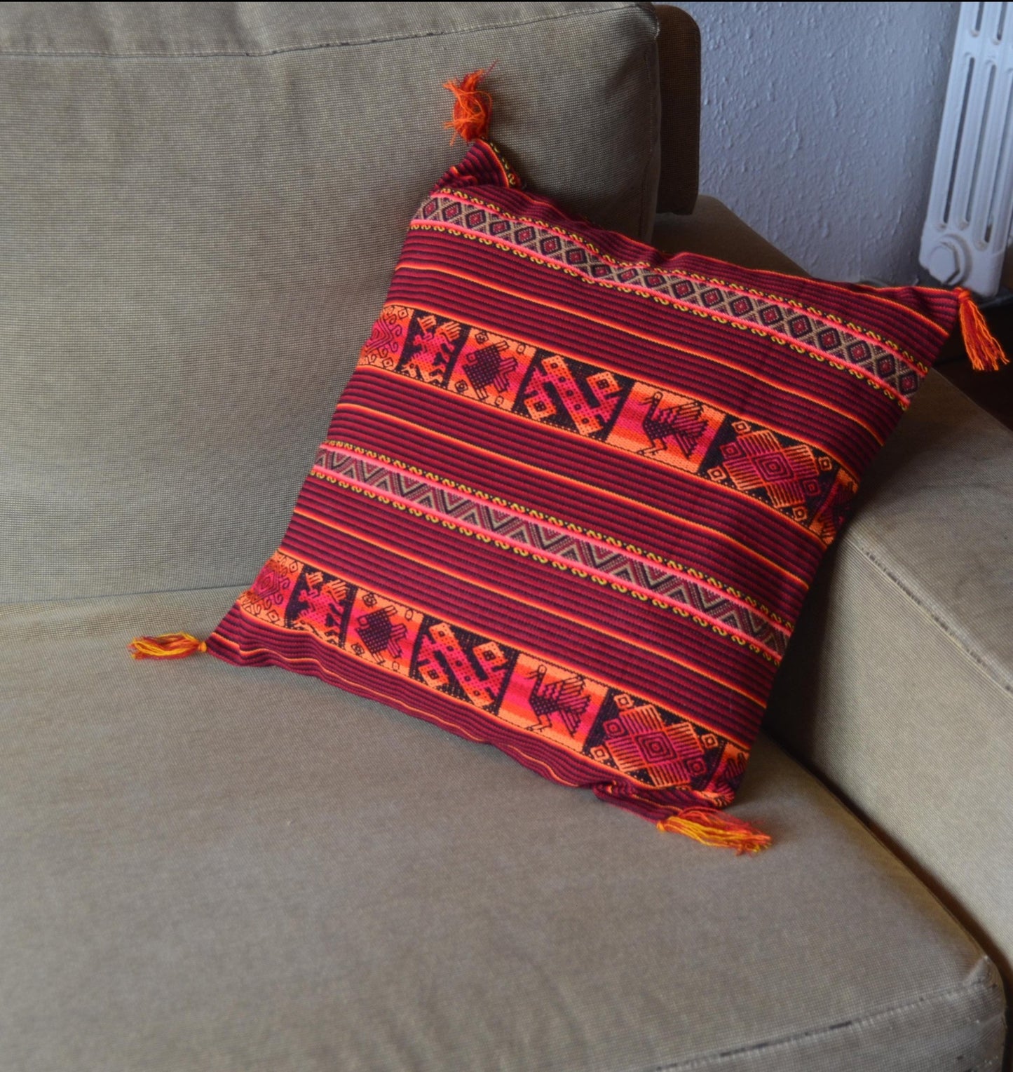 Handmade Peruvian woven alpaca pillow in red with orange ethnic patterns and tassels.