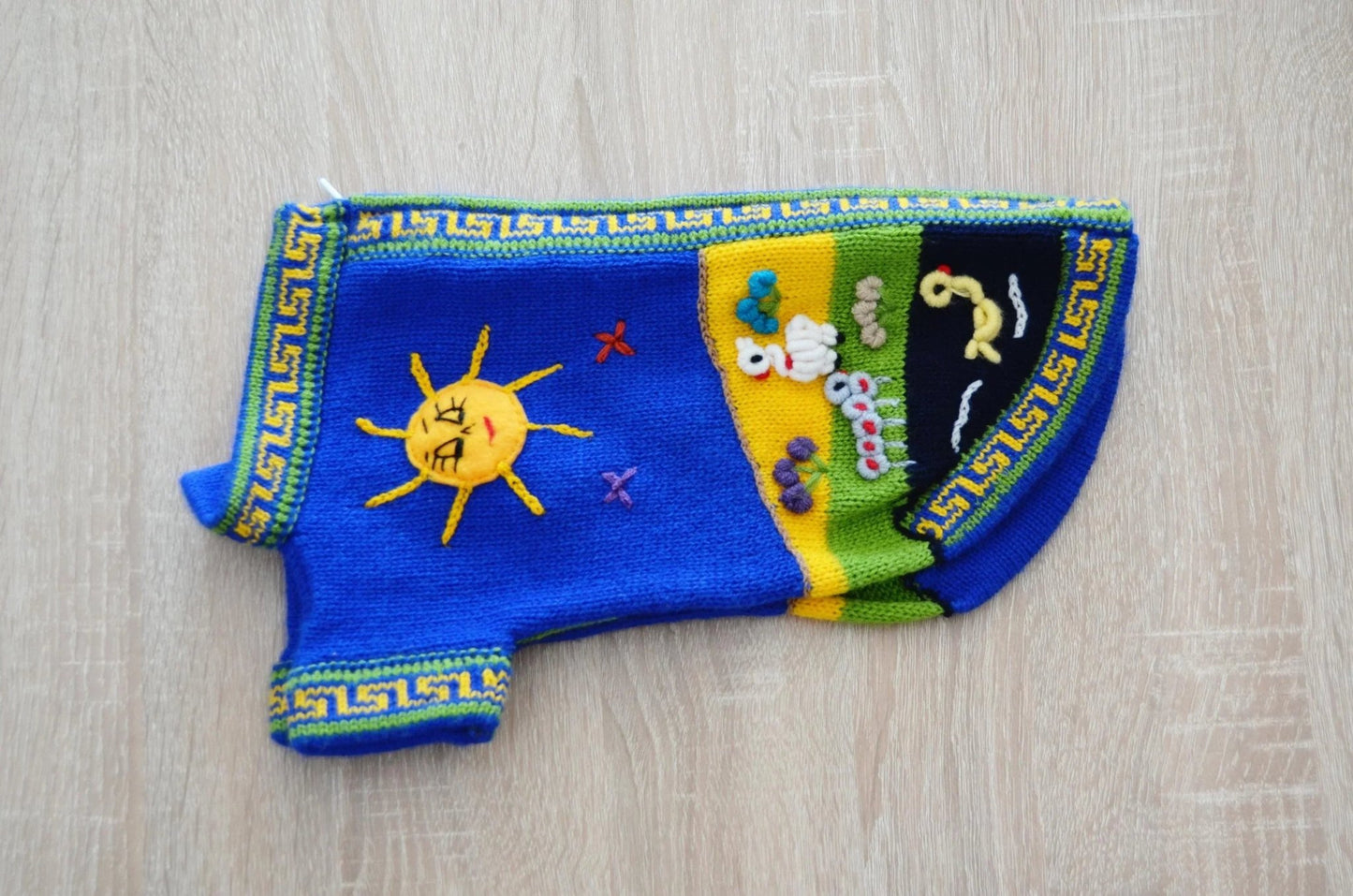 Handmade navy blue alpaca dog sweater with sun and nature embroidery, geometric trim.