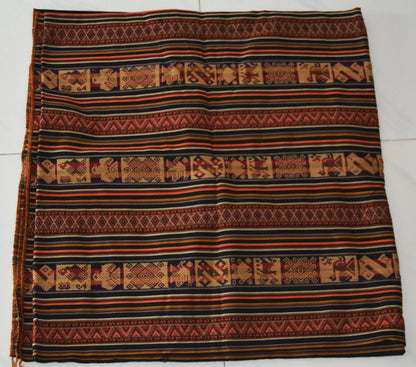 Handmade alpaca textile with brown, black, and orange geometric and animal patterns.