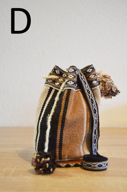 Handmade small alpaca shoulder bag with brown, black, and cream stripes, and patterned strap with pom-poms.