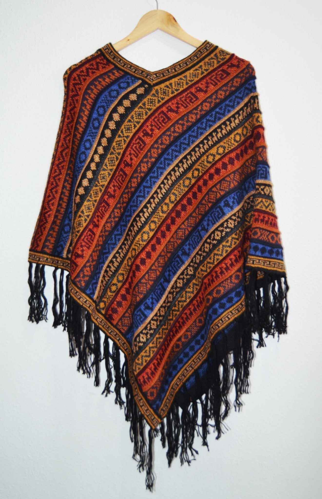 Handmade Peruvian alpaca poncho with colorful geometric patterns and black fringe trim.