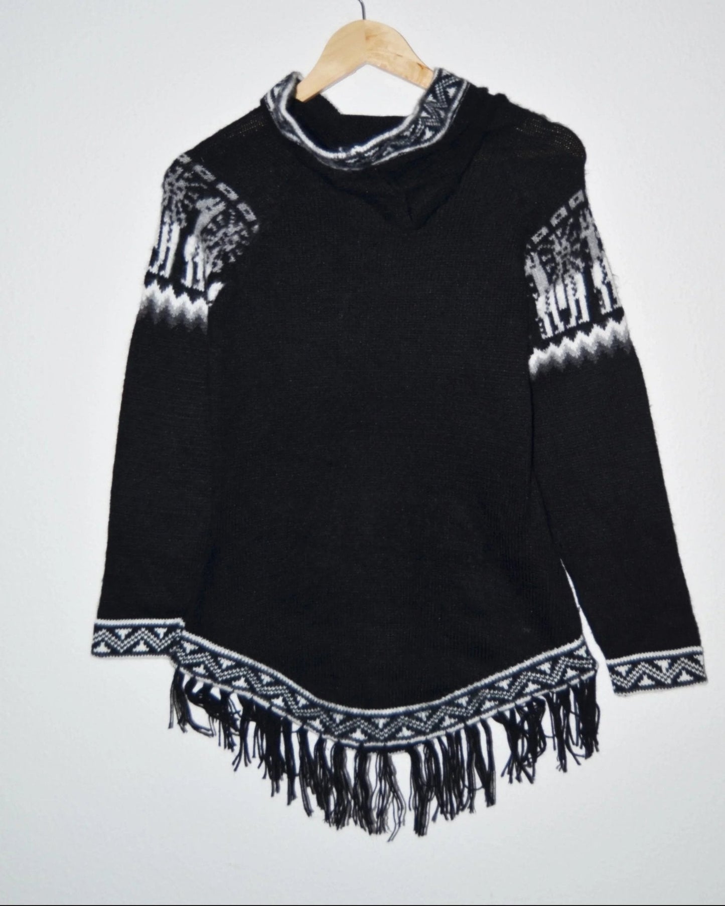Black handmade alpaca sweater with white geometric patterns, fringed hem, and high collar.