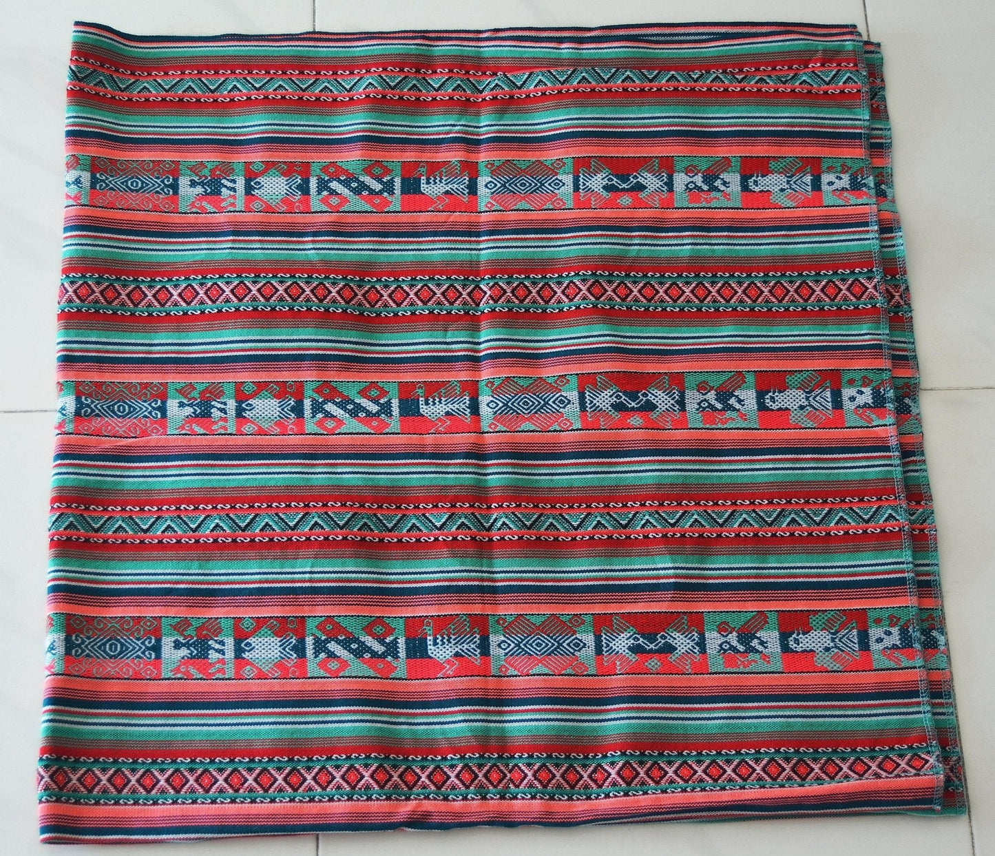 Handmade alpaca blanket with colorful geometric and animal patterns in red, blue, and green tones.